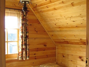 Mała sypialnia w domku letniskowym, zbudowanym z bali drewnianych