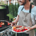 Cropped image of handsome man is making grill barbecue outdoors on the backyard. Bbq party.